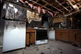 Fire-damaged kitchen needs electrical repair for exposed ceiling and appliances.